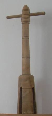wooden cylinder with notches on long handle with cross-piece near top