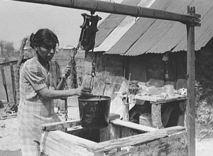 Woman at well with metal bucket